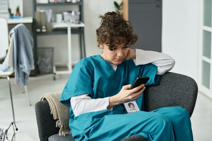 Nurse in a hospital break room checking a smartphone